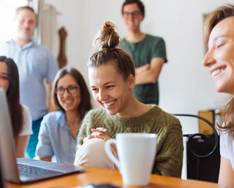 Grupo de jovens sorrindo em volta de um notebook
